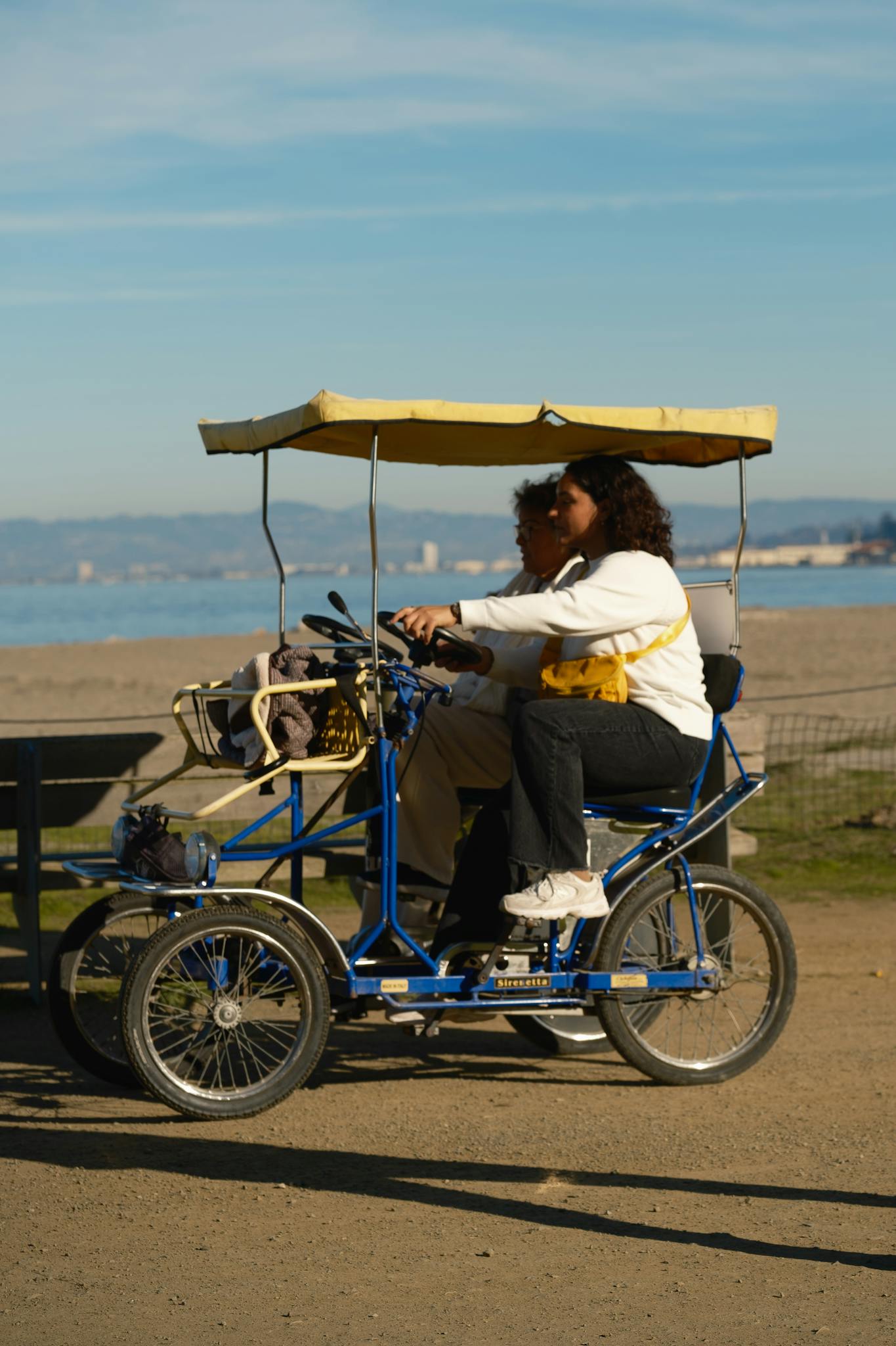 A couple enjoys a sunny ride on a pedal car by the beach in Los Angeles, California.