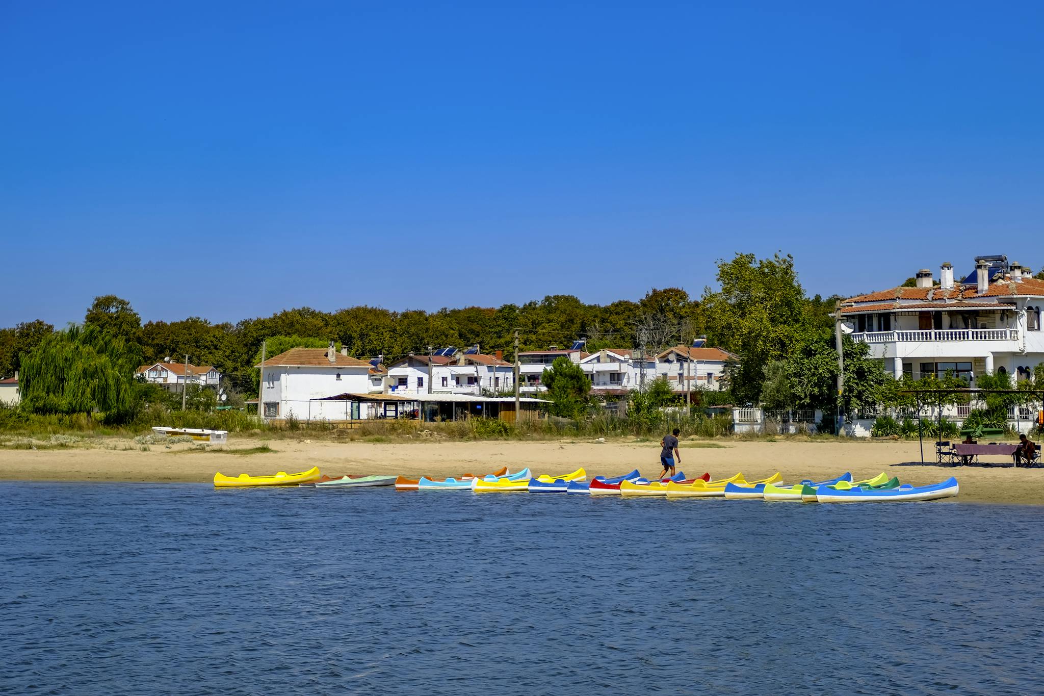 Scenic view of colorful canoes lined up on a tranquil sandy beach in Igneada, perfect for summer leisure and recreation.